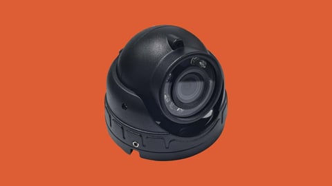 Black dome security camera with lens against orange background