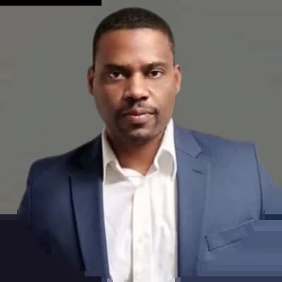 Professional headshot of a man wearing a blue blazer and white dress shirt against a gray background