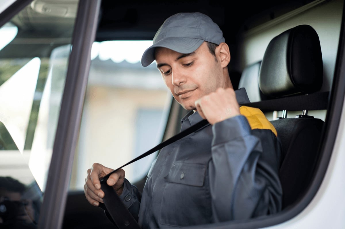 Service worker in uniform and cap sitting in vehicle cab, holding a pressure washer wand