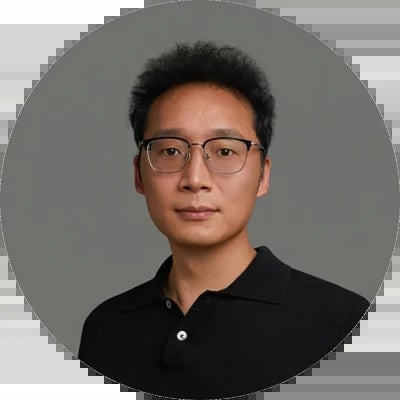 Asian man wearing glasses and black polo shirt in circular portrait against gray background